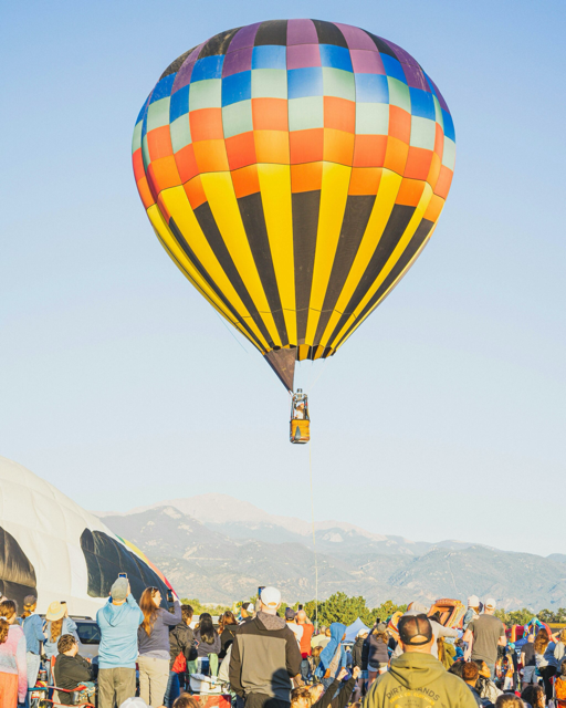 Foto eines startenden Heißluftballons, der farbenfroh und mächtig in einen sonnigen Himmel aufsteigt